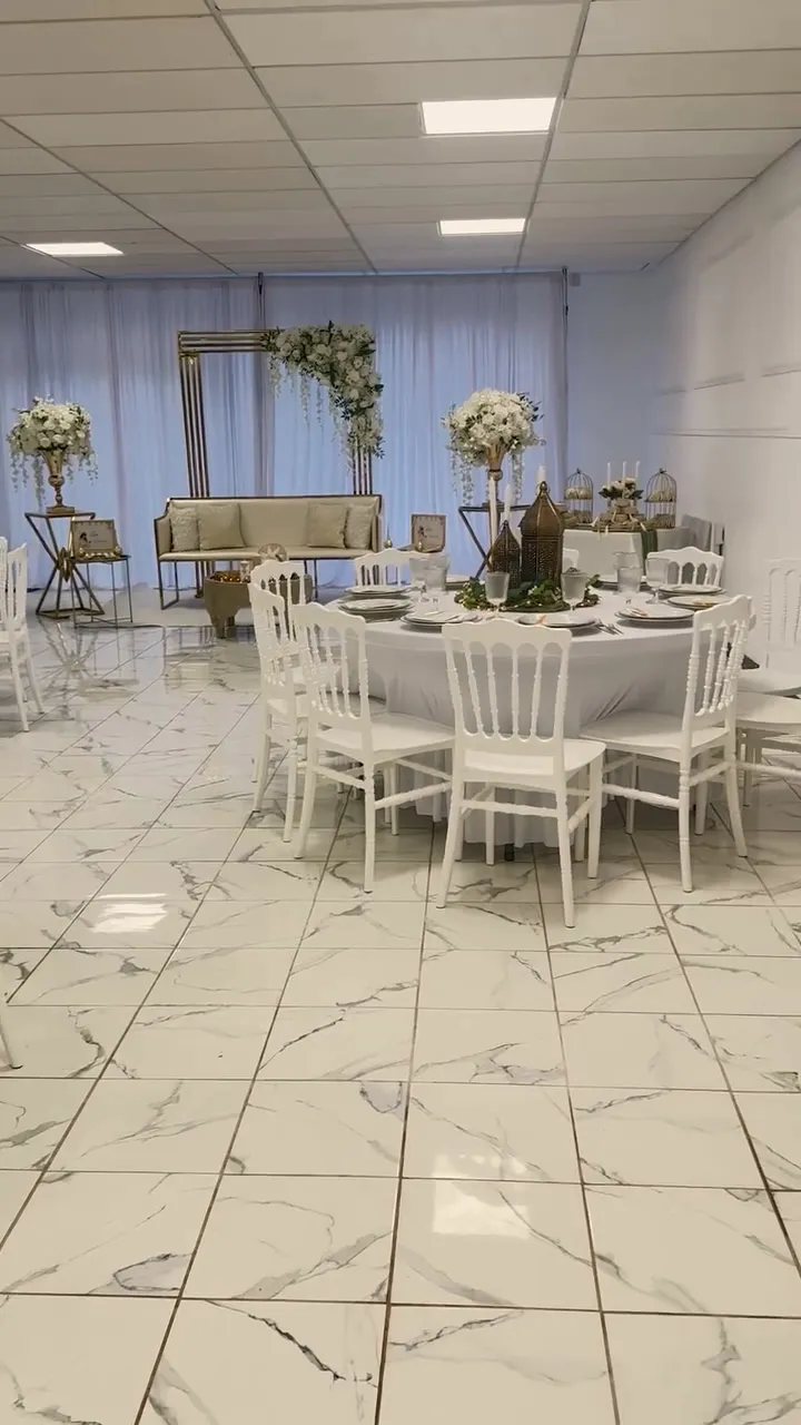 Coin des mariés avec canapé, arche dorée fleurie et compositions de fleurs blanches sur colonnes