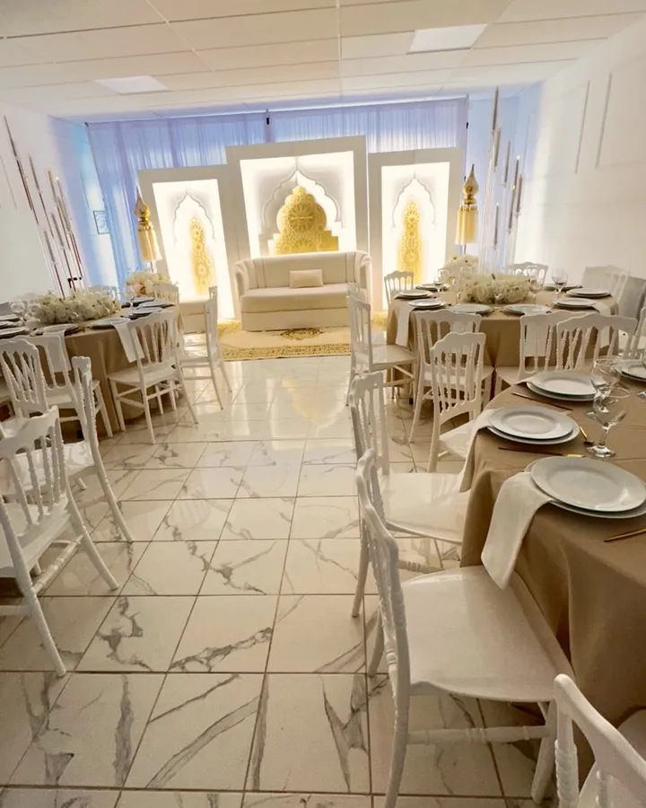 La salle Amoria dressée pour une réception : tables rondes en nappes ivoire doré, chaises Napoléon blanches et arches orientales lumineuses