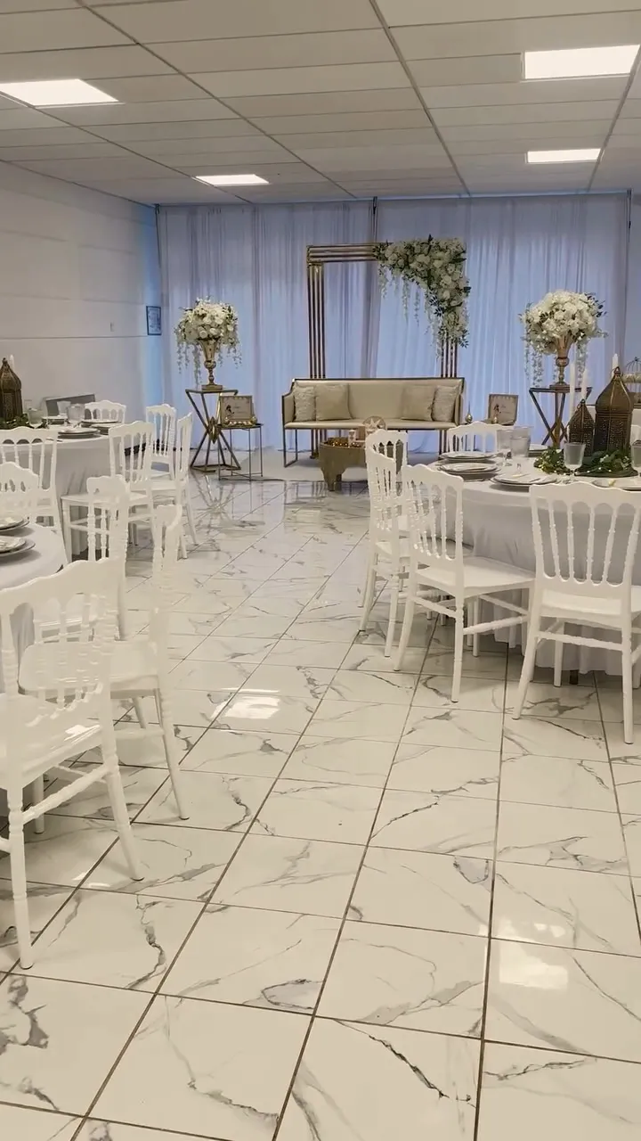 Vue d'ensemble de la salle de 180 m² : tables rondes, coin des mariés et voilages blancs